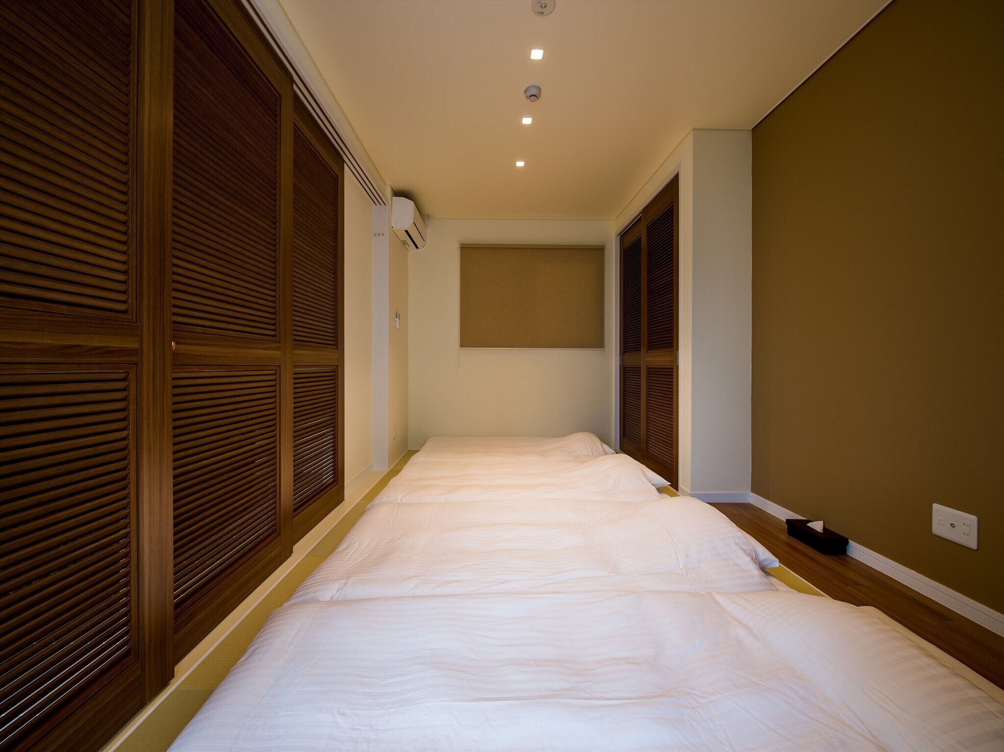 A bedroom with a large bed, wooden sliding doors, and a ceiling light.