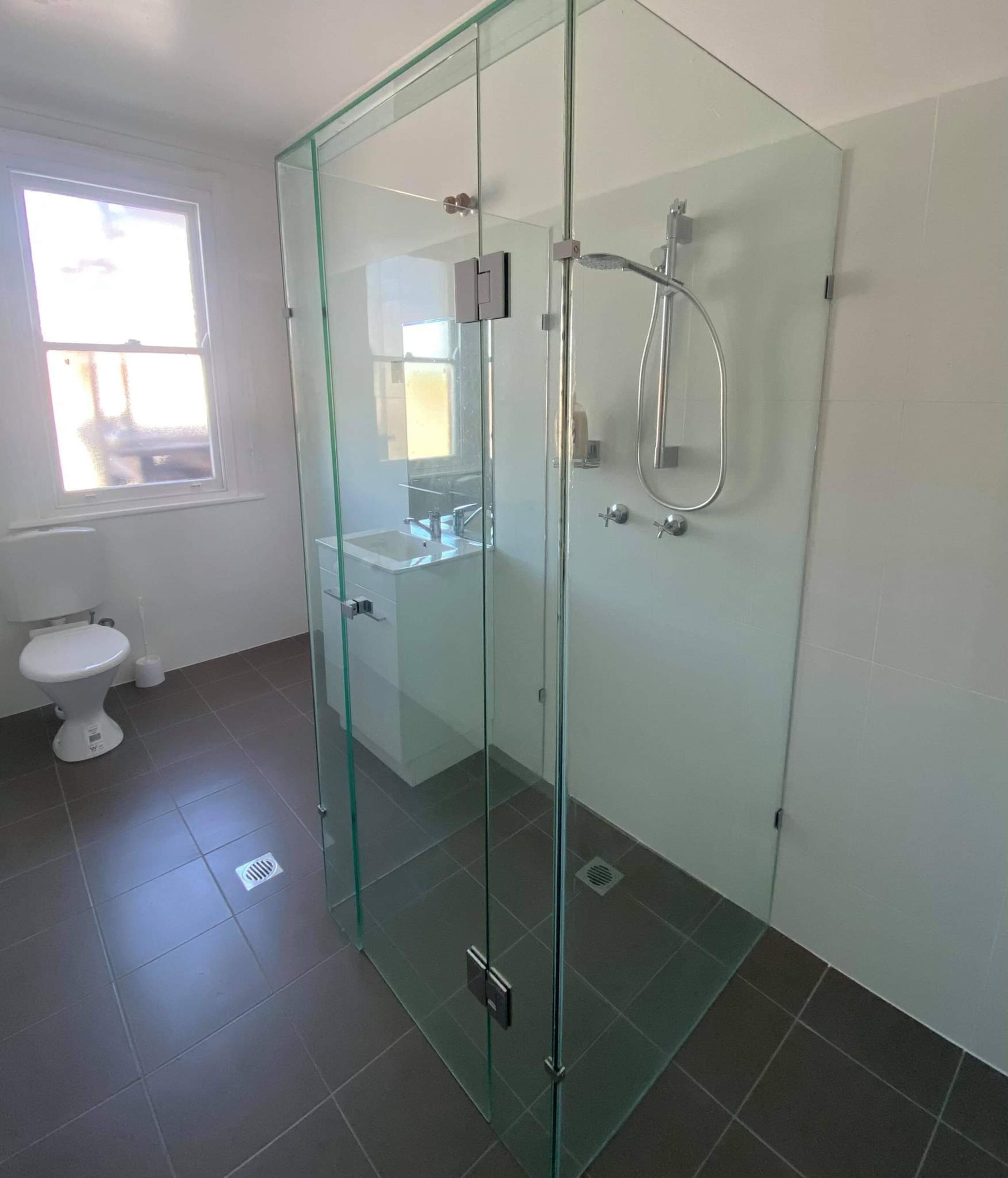 Un baño moderno con ducha envuelta en vidrio, inodoro y lavamanos.