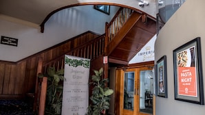 A hotel lobby with a wooden staircase, a sign for the Imperial Bistro, and a poster advertising Pasta Night. - Imperial Hotel Coonabarabran (Coonabarabran)