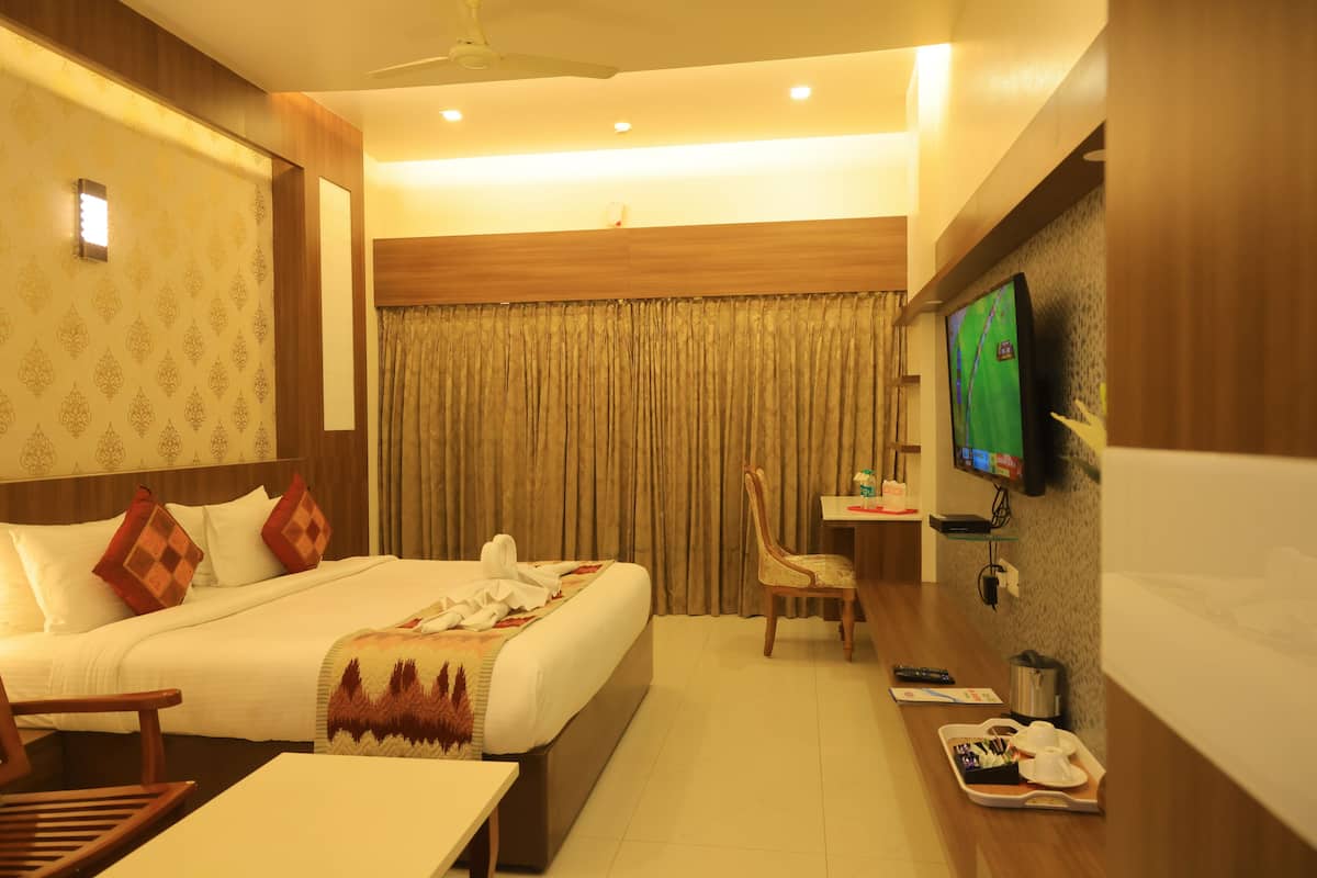 A hotel room with a bed, a desk, a chair, a television, and a window with curtains.