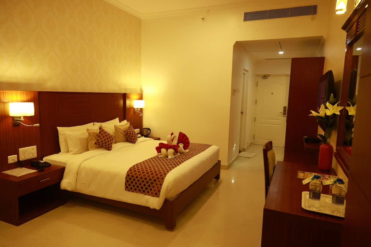 A hotel room with a large bed, bedside lamps, a nightstand, a dresser, and a mirror.