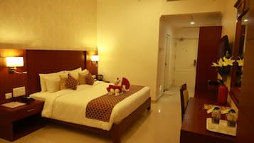 Una habitación de hotel con una cama grande, lámparas de noche, una mesita de noche, un aparador y un espejo.