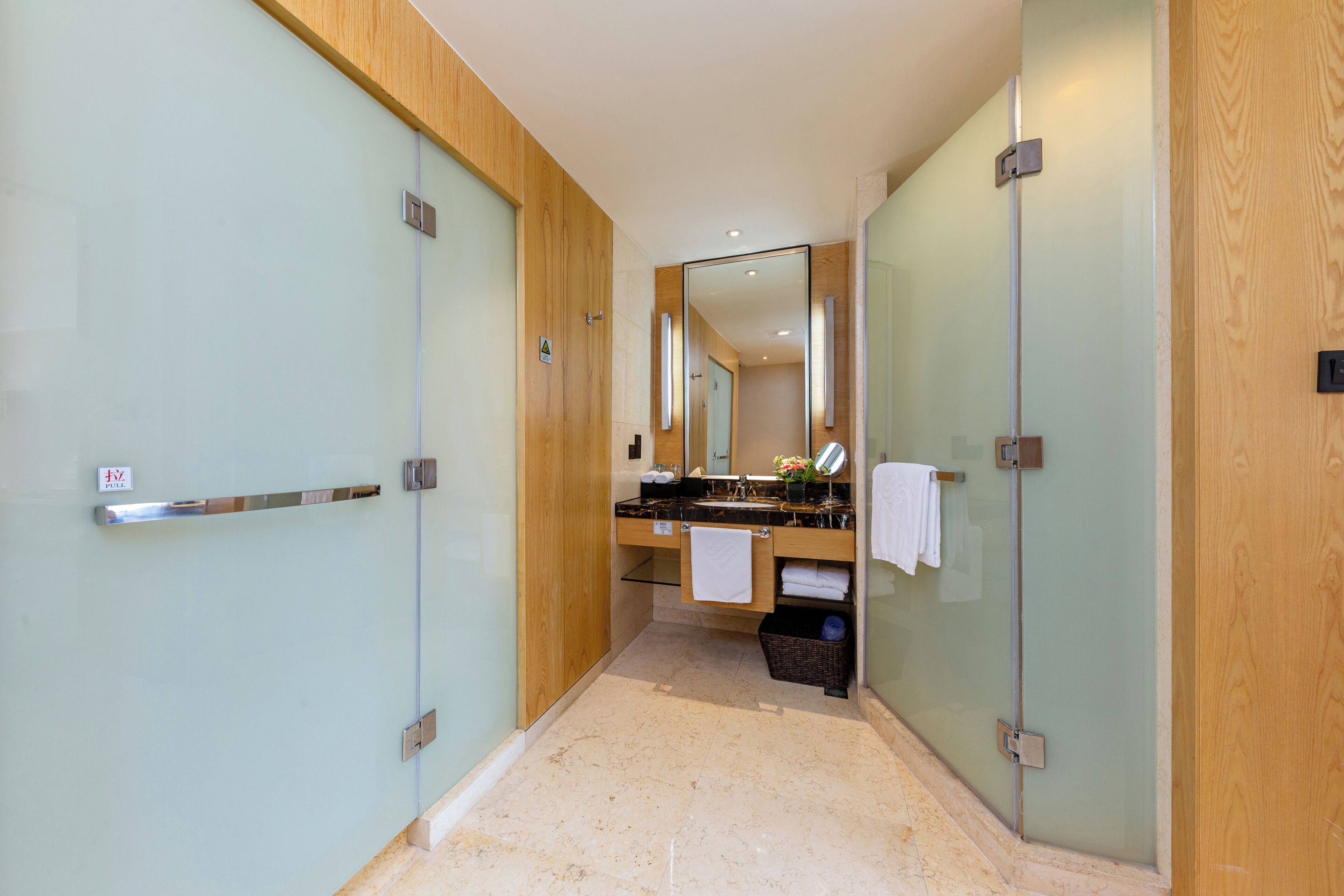 A modern bathroom with a glass shower enclosure, a wooden vanity, and a mirror above the sink.