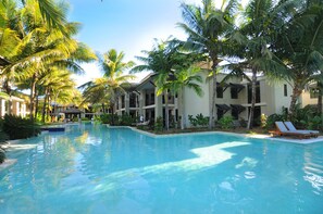 Una piscina rodeada de palmeras y un edificio con varios balcones.