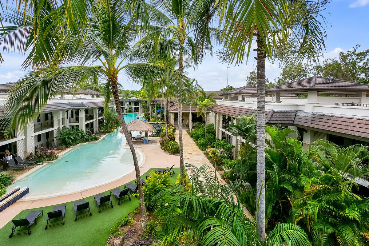 Un resort con piscina, sillones de descanso y palmeras.