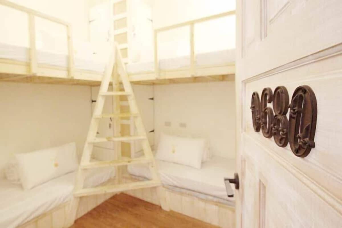 A room with bunk beds, a ladder, and a door with a number plaque.