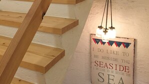 Un escalier en bois, avec une pancarte accrochée au mur sur laquelle on peut lire : « J’aime beaucoup être près de la mer. »