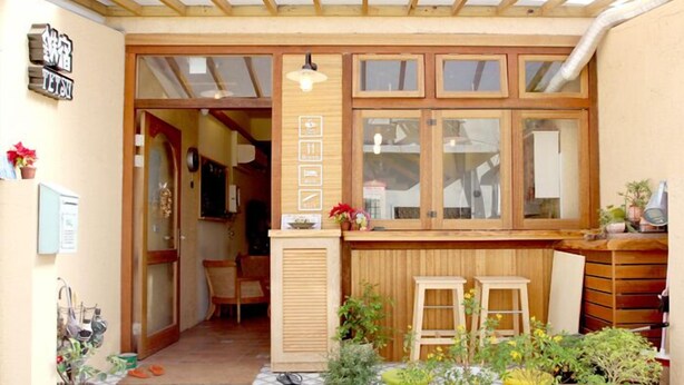 Une pièce chaleureuse avec un plafond en bois, une grande fenêtre à carreaux et une petite table en bois.