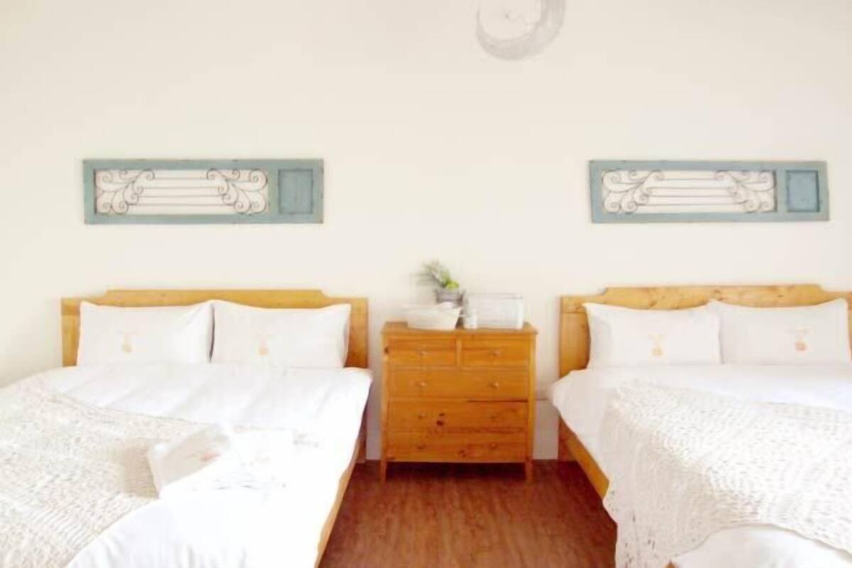 A double room with two beds, a wooden dresser, and decorative wall art.