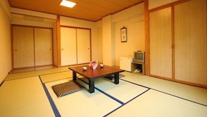 Um quarto japonês tradicional com tatames, uma mesa baixa com um vaso e portas deslizantes.