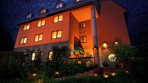 Um hotel com vários andares, uma entrada chamativa com uma placa e um céu estrelado ao fundo.