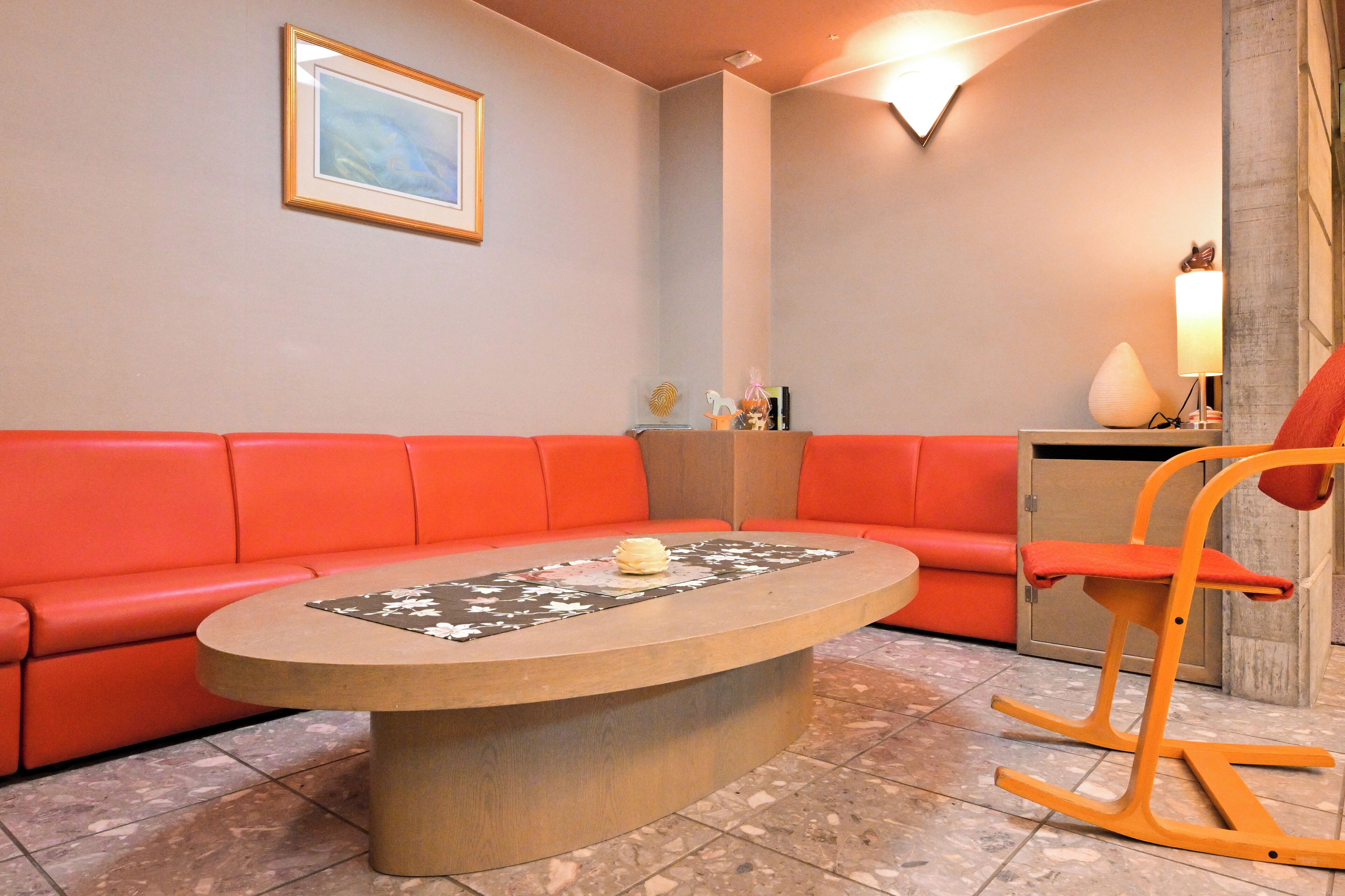 A modern living room with a red sofa, a round coffee table, and a wooden rocking chair.