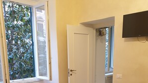 Quarto com cama, radiador, janela e porta de acesso a um banheiro.