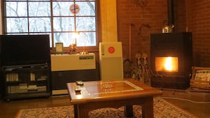 A cozy living room with a fireplace, a television, and a coffee table. - Pension Marionette (Hakuba)