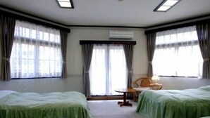 A hotel room with two beds, a small table, and a chair. - Pension Marionette (Hakuba)