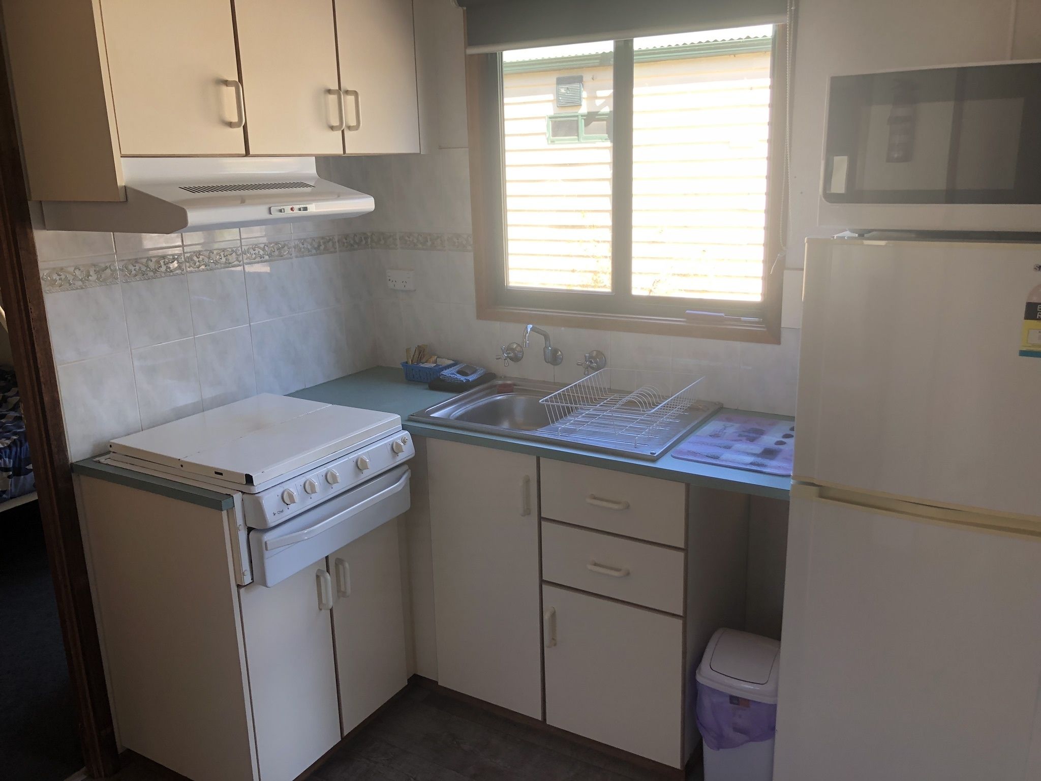 Een kleine keuken met een fornuis, oven, spoelbak en koelkast.