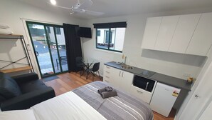 A compact hotel room with a bed, a small kitchenette, a dining area, and a sliding glass door to the outside. - G'day Parks Ararat (Ararat)