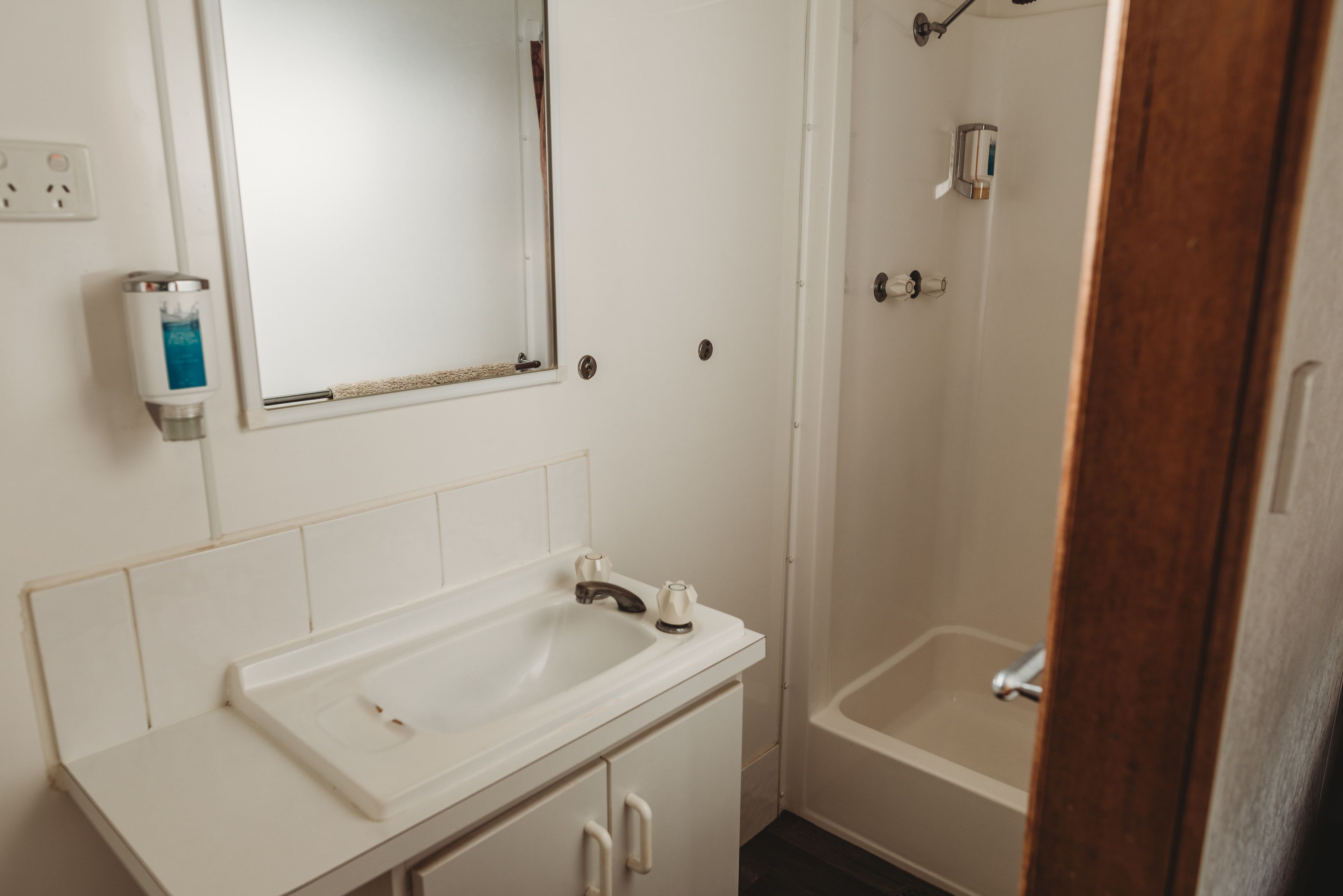 A bathroom with a white sink, mirror, and shower.