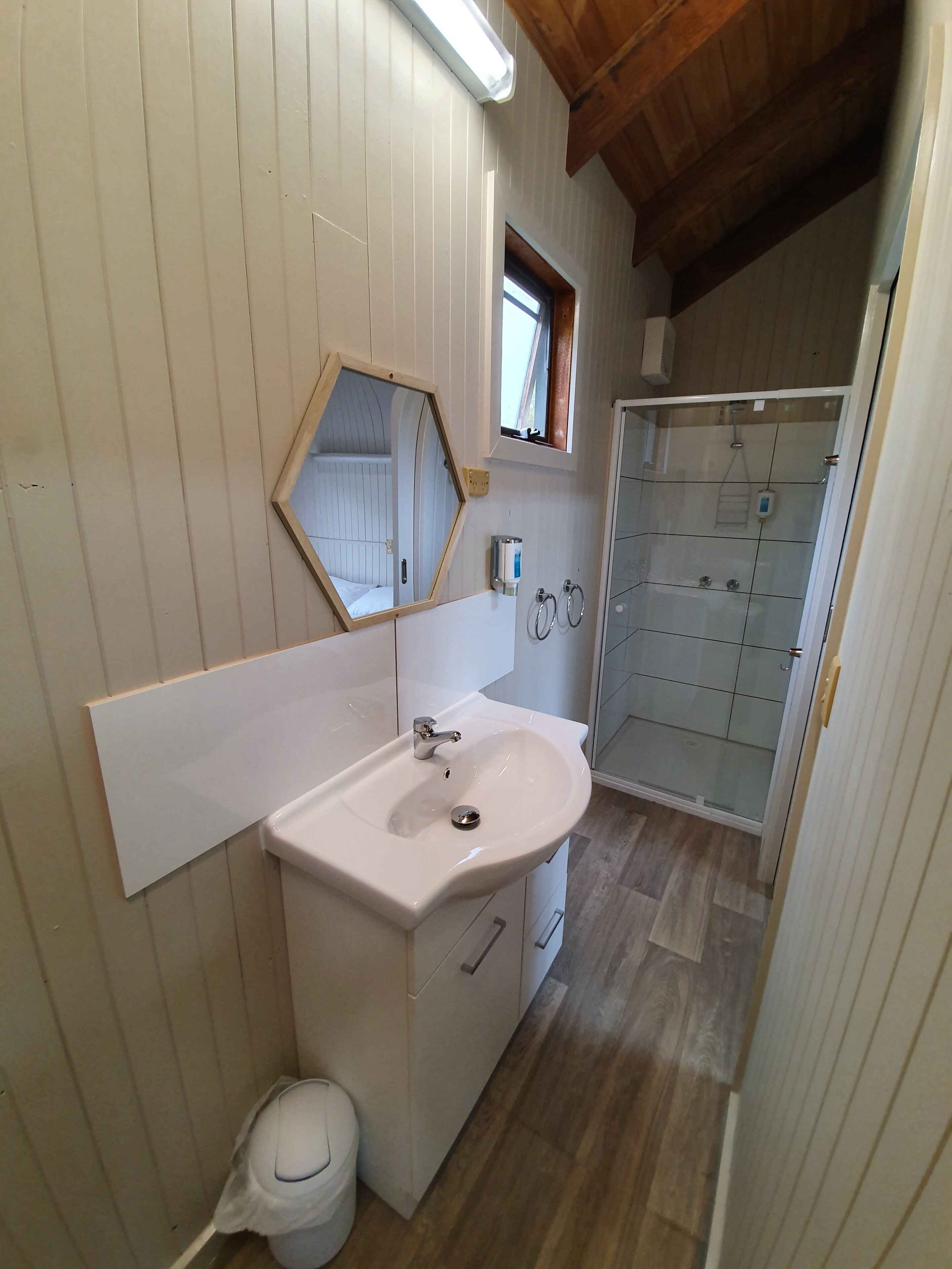 A bathroom with a white sink, mirror, and wooden panel walls.