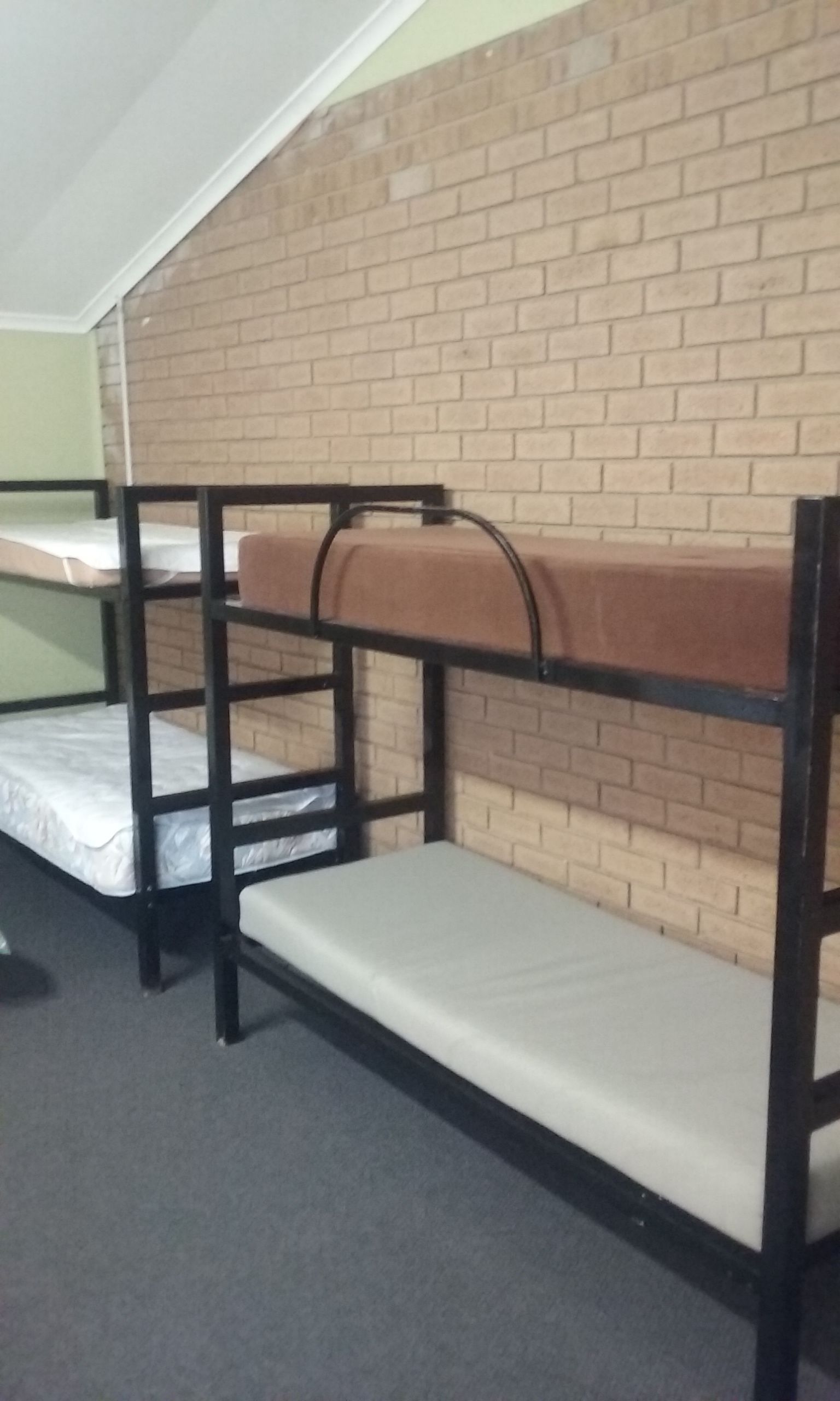 Een slaapkamer met een stapelbed, een bakstenen muur en een raam.
