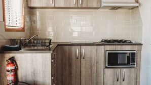 A kitchen with wooden cabinets, a microwave, and a gas stove. - G'day Parks Ararat (Ararat)