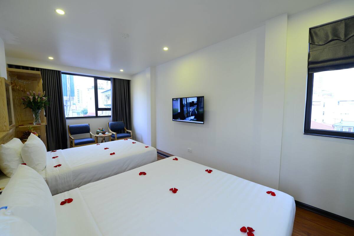 Ein Hotelzimmer mit zwei Betten, einem Fernseher, einem kleinen Tisch und einem Stuhl.
