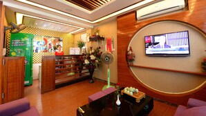 A hotel lobby with wooden paneling, a reception desk, a television, and a green beverage cooler.