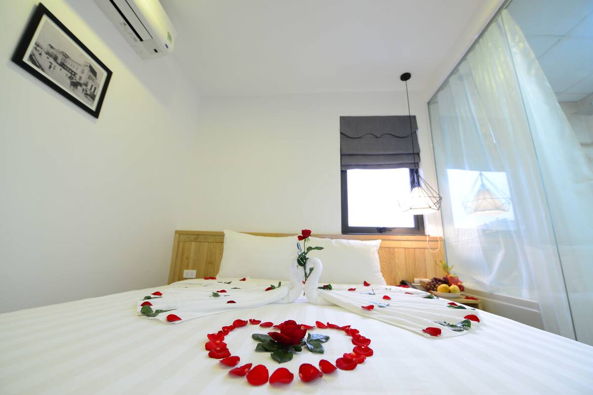 Ein Hotelzimmer mit einem ordentlich bezogenen Bett, einem gerahmten Bild an der Wand und einem Fenster mit Vorhängen.