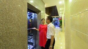 A hotel lobby with a marble floor, a reception desk, and a potted plant.
