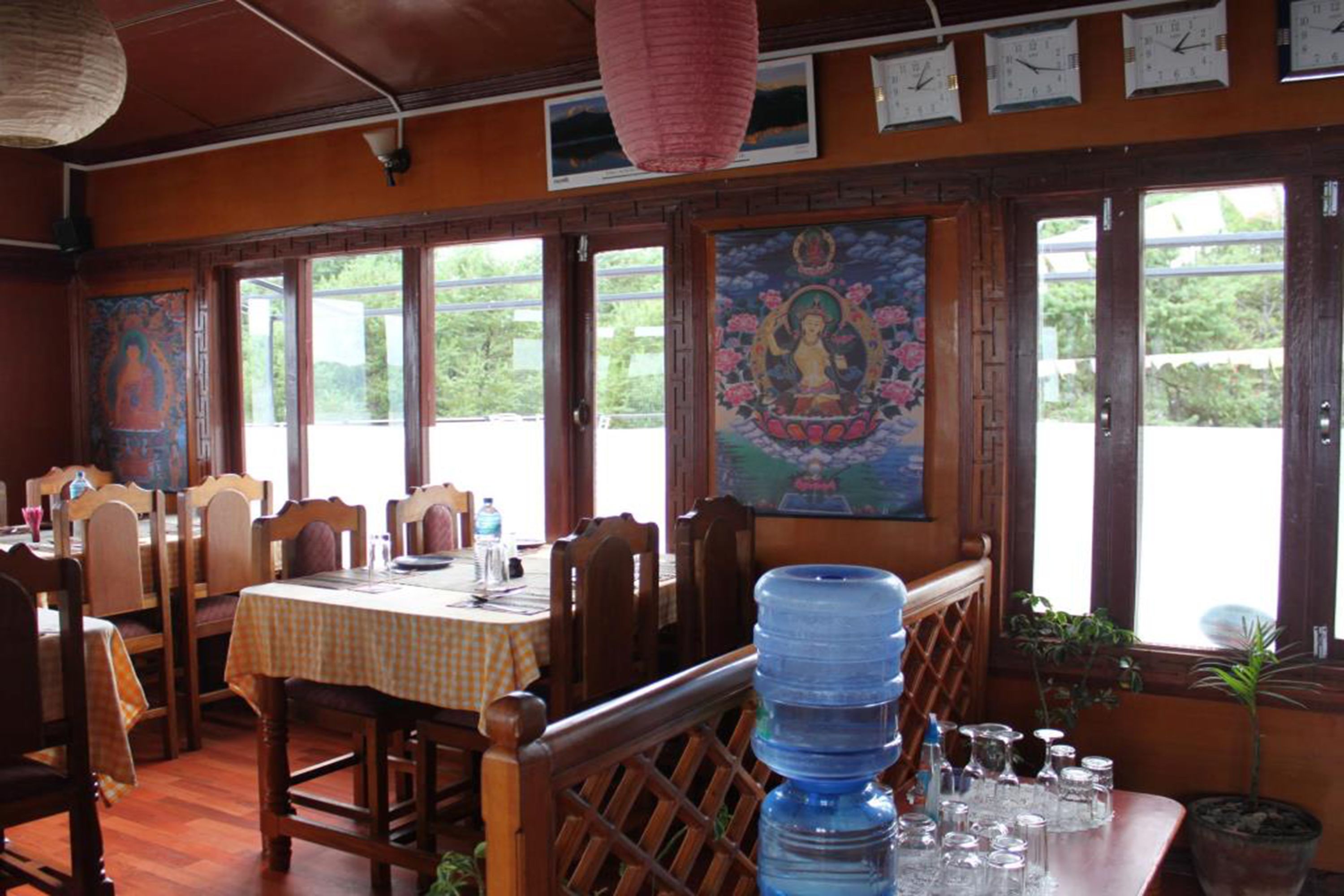 Un restaurant avec des meubles en bois, une table recouverte d’une nappe à carreaux et un grand distributeur d’eau.