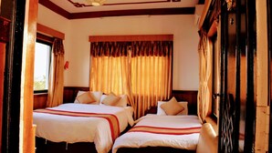 A hotel room with two beds, a large window with curtains, and a wooden ceiling.