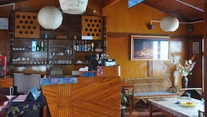 A traditional wooden interior with a bar area, woven furniture, and hanging paper lanterns.