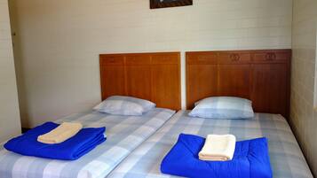 Dos camas individuales con cabeceros de madera, ropa de cama a cuadros azul y blanco, y toallas dobladas.