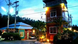 A two-story building with a balcony on the upper floor, a signboard, and a vehicle parked in front. - Somjainuk Resort 2 (Pluak Daeng)