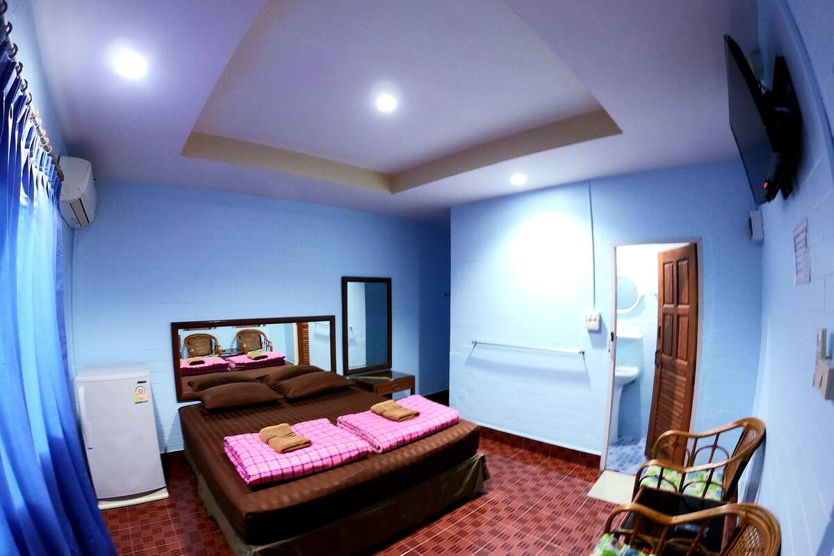 A bedroom with a bed, a chair, a mirror, and a wardrobe.
