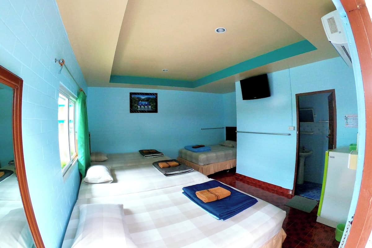 A compact room with a bed, a small table, a wall-mounted TV, and a window with curtains.