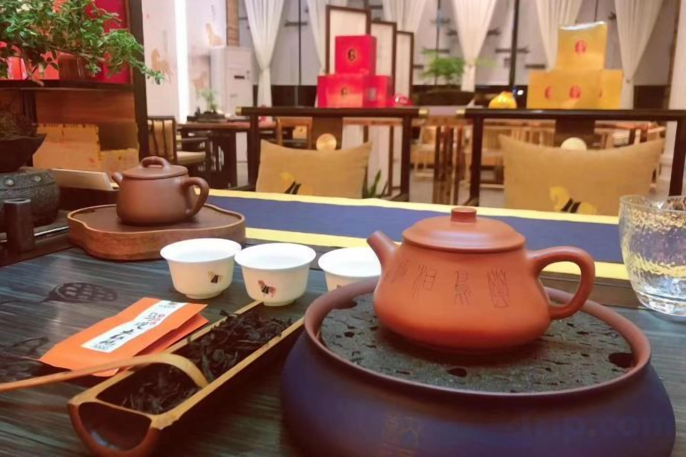 Una taula amb un colador de te, tasses i un plat de fulles de te.