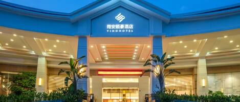 A hotel entrance with a modern design, featuring a prominent entrance, a staircase leading up, and a well-lit facade.