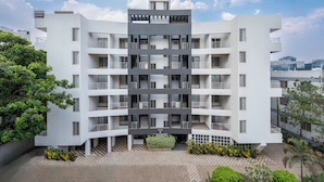 Un edificio moderno de varios pisos con un patio central, balcones y techo plano.