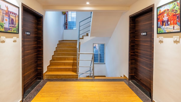 Un pasillo moderno de hotel con puertas de madera, una escalera y un ventanal.