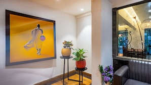 Un interior moderno con un cuadro abstracto grande, una planta en maceta y un sofá de cuero.