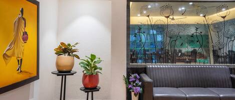A modern interior with a sofa, two potted plants, and a decorative glass panel with floral designs.