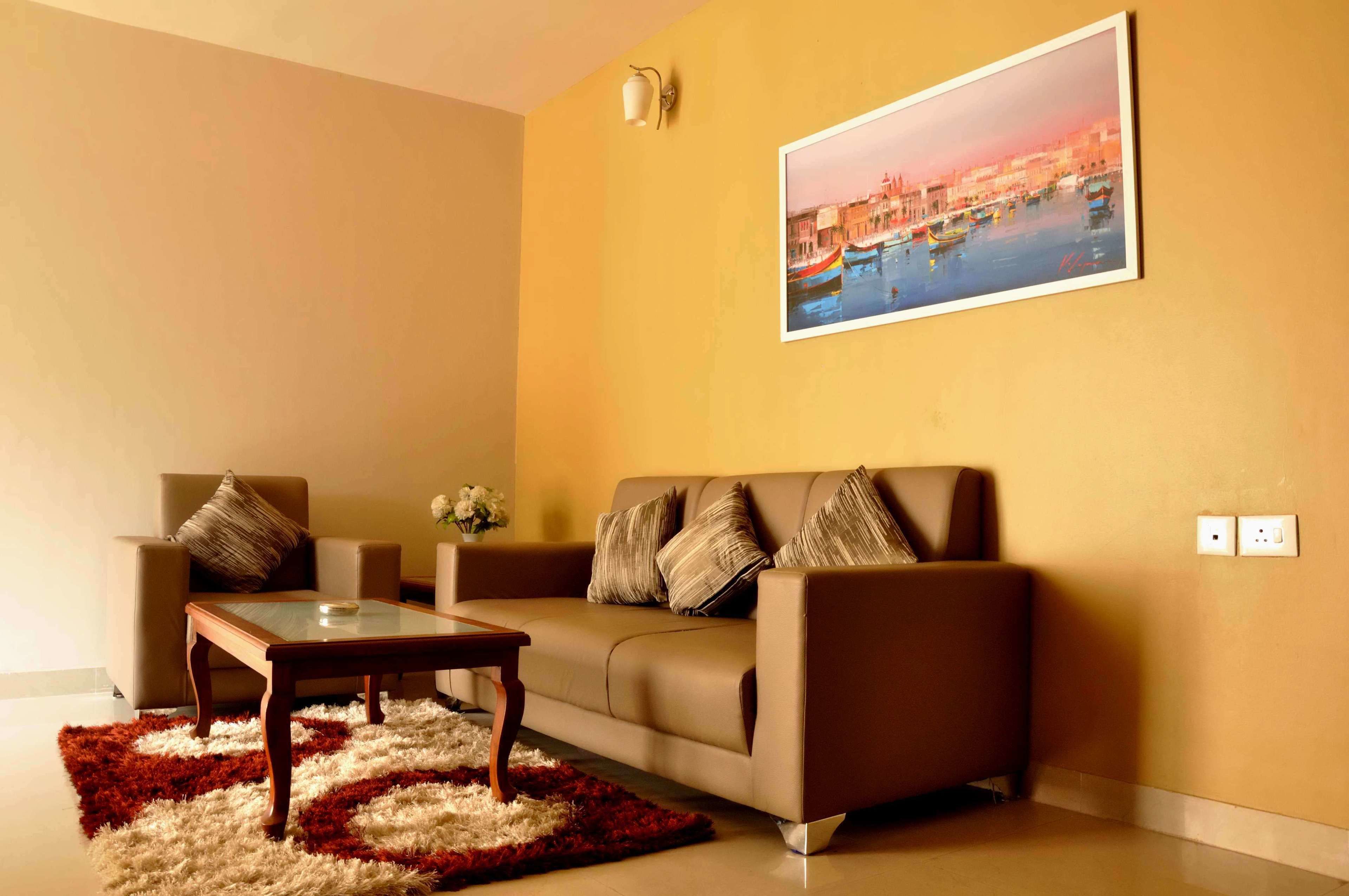 A living room with a sofa, a coffee table, and a painting on the wall.