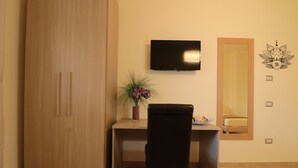 A room with a wooden wardrobe, a desk with a chair, a television, and a mirror. - B&B Pietrarsa (Portici)