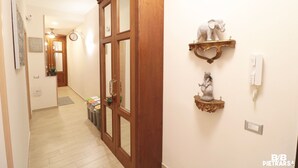 A hallway with wooden doors, a clock, and decorative wall shelves. - B&B Pietrarsa (Portici)