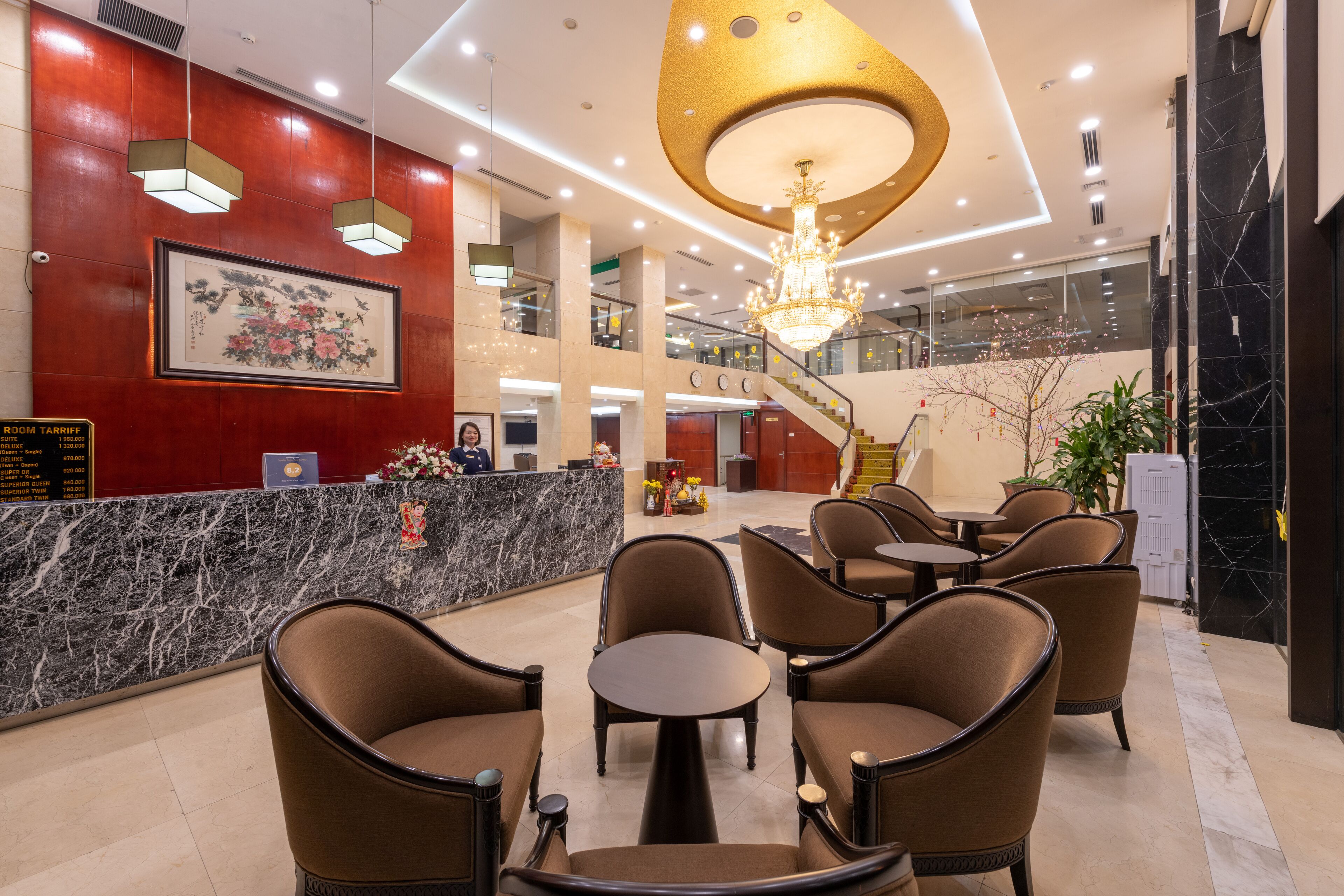 Eine Hotelhalle mit einer Rezeption, einer Sitzecke und einer Treppe zu den oberen Etagen.
