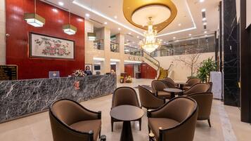 Eine Hotelhalle mit einer Rezeption, einer Sitzecke und einer Treppe zu den oberen Etagen.