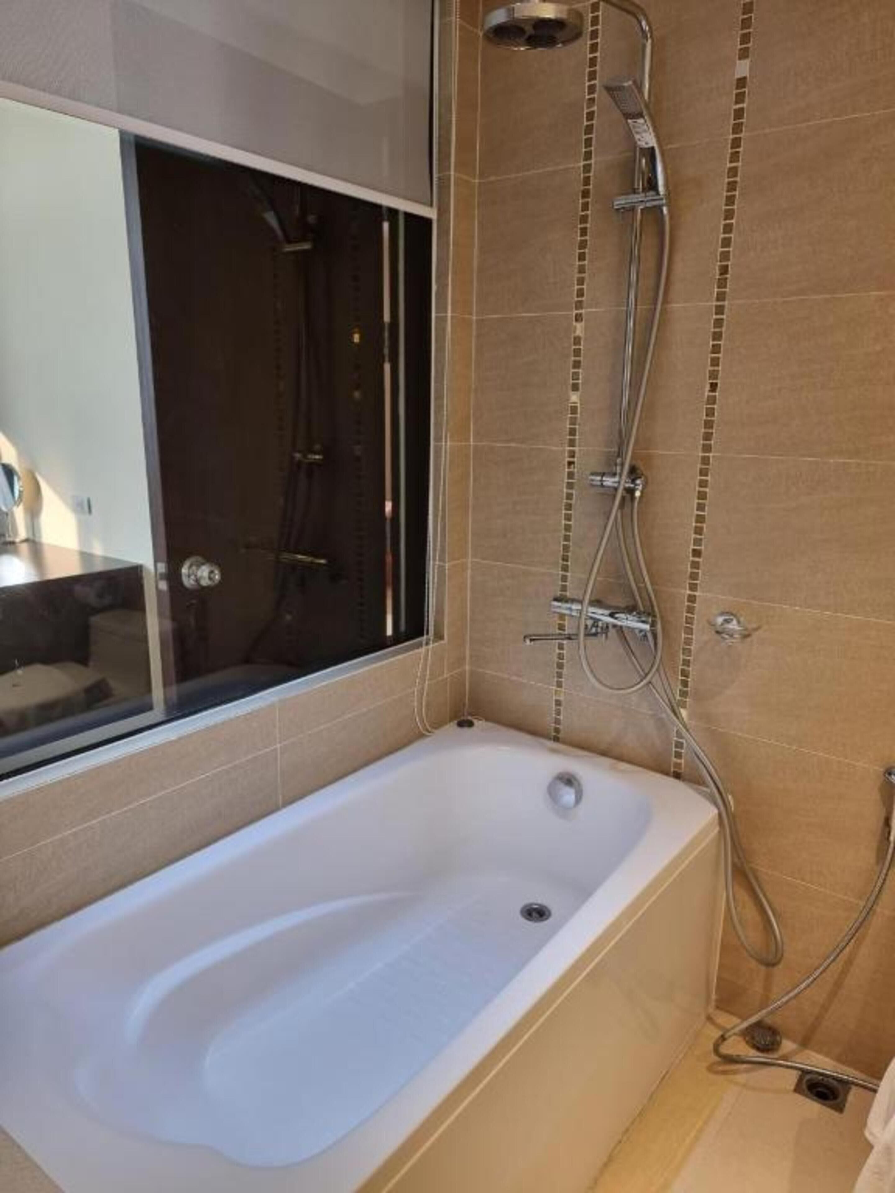 Un baño moderno con una bañera independiente, cabina de ducha con mampara de vidrio y paredes con azulejos.