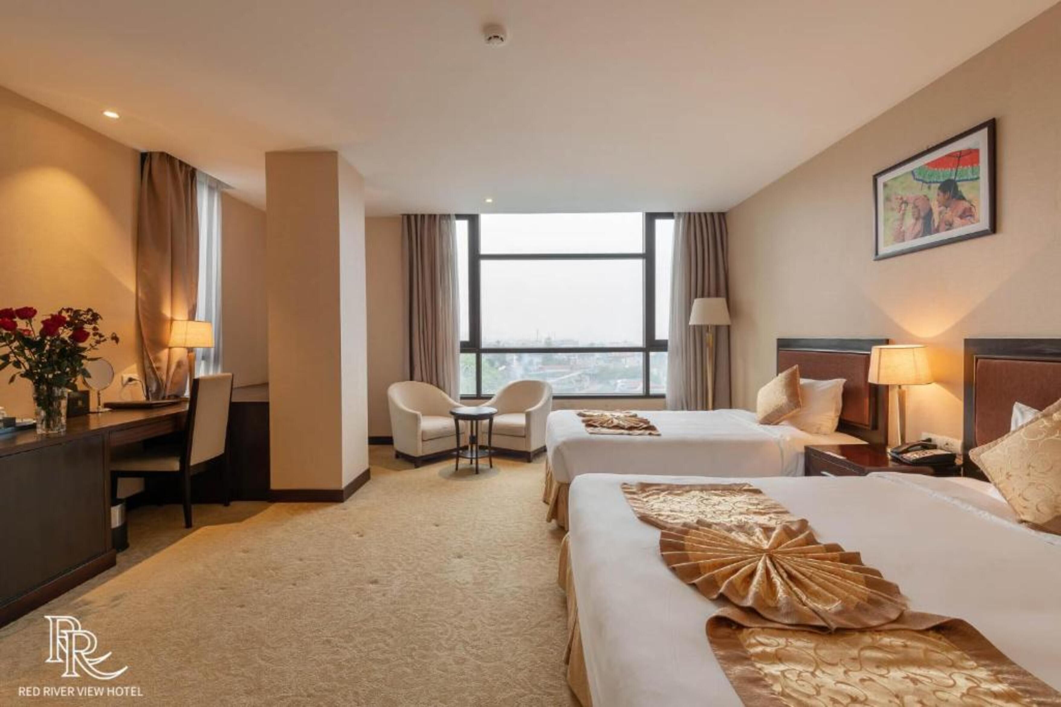 Habitación de hotel con dos camas, un escritorio, una silla, una mesita y una ventana con cortinas.