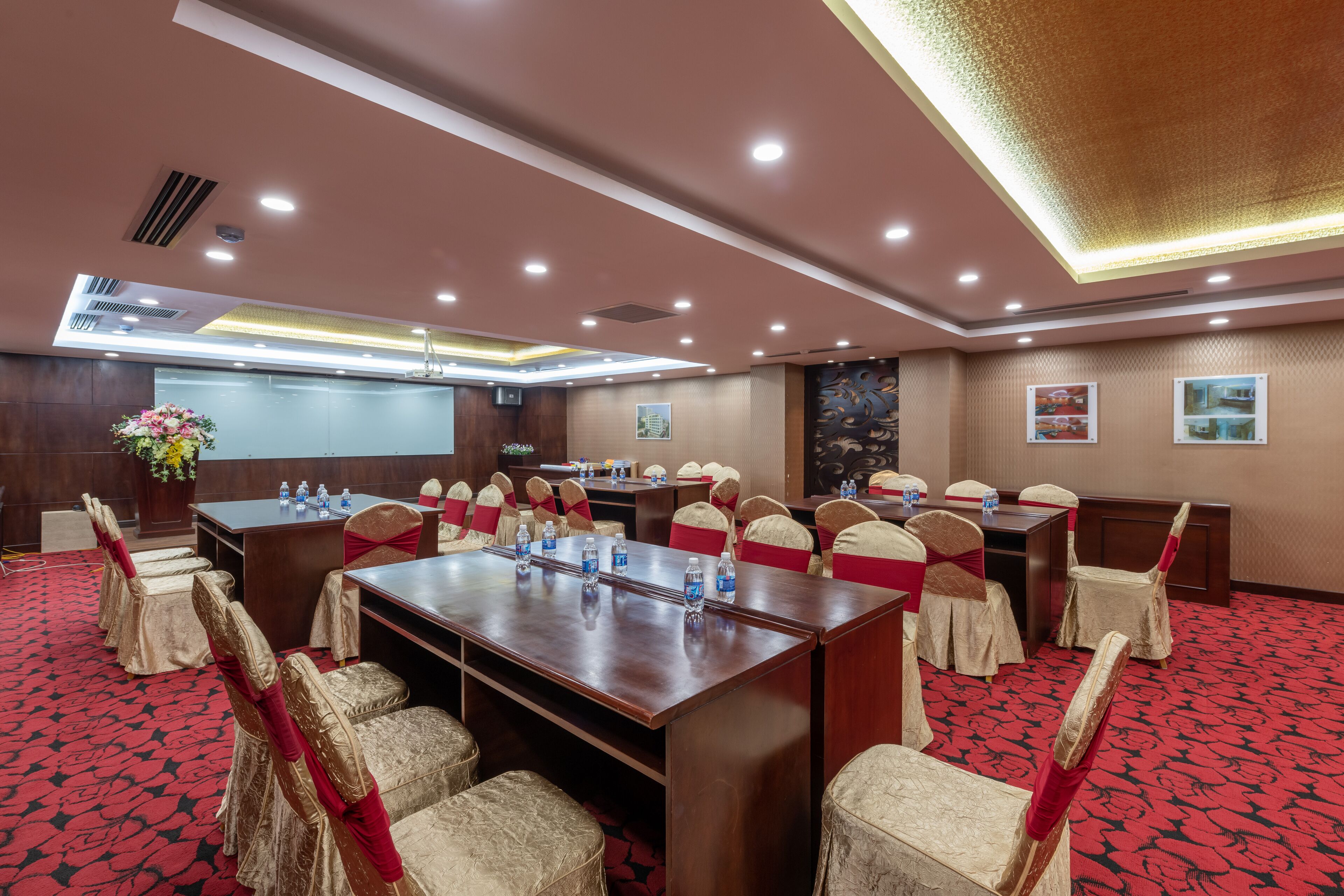 A conference room with a long table, chairs, and a projector screen.